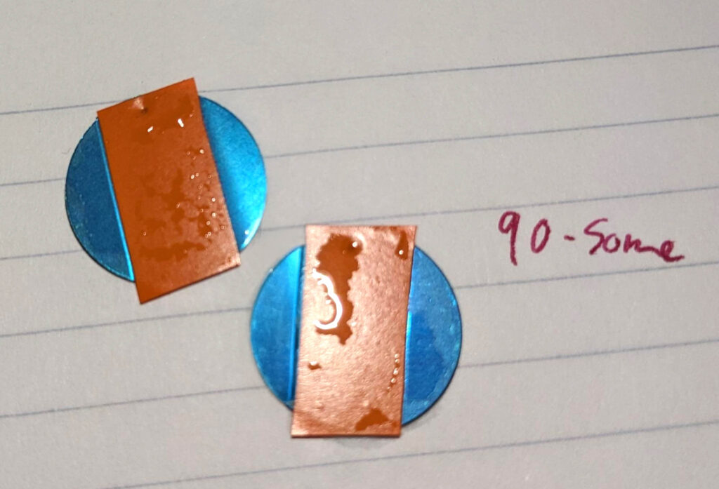 Blue metal disks with stripes of orange electrical tape covering most of the center.