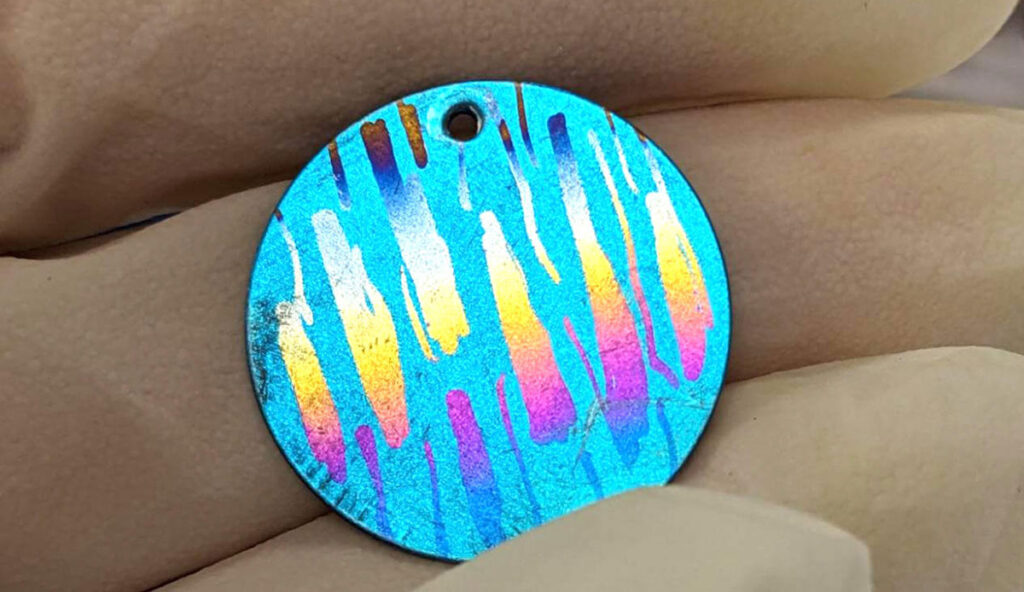 Close up of a blue metal disk with patches of bright rainbow colors.